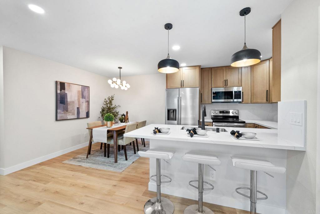 3591 Ruffin Rd Unit 125, San Diego, CA 92123 - kitchen with appliances with stainless steel finishes, a peninsula, light countertops, light wood-style floors, and a breakfast bar