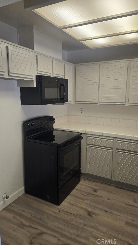 13104 Glen Ct Unit 46, Chino Hills, CA 91709 - kitchen featuring baseboards, tile countertops, dark wood-style flooring, and black appliances
