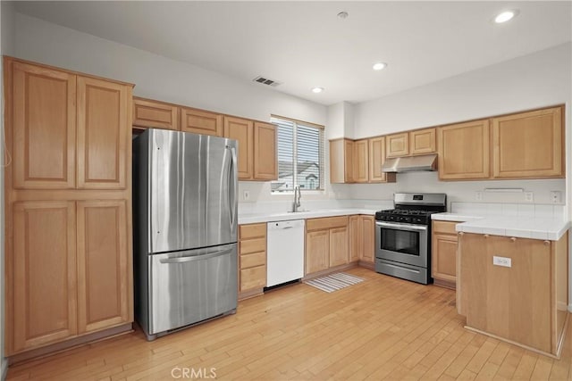 kitchen featuring light brown cabinetry, under cabinet range hood, visible vents, light wood-type flooring, and appliances with stainless steel finishes