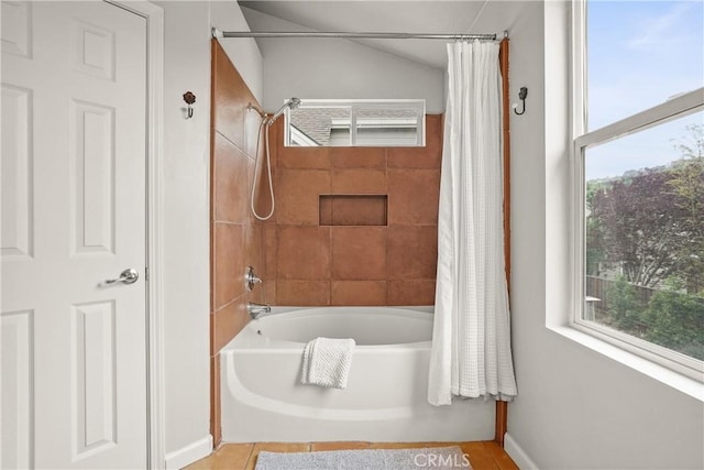 bathroom with shower / tub combo with curtain, a healthy amount of sunlight, and baseboards