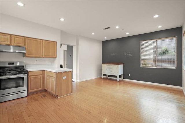 kitchen featuring under cabinet range hood, stainless steel gas range oven, light countertops, visible vents, and light wood-style flooring