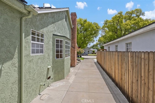 3432 N Arrowhead Ave, San Bernardino, CA 92405 - view of side of home featuring stucco siding, fence, and a chimney