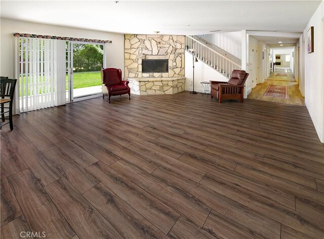 unfurnished living room with a stone fireplace and dark wood-style flooring