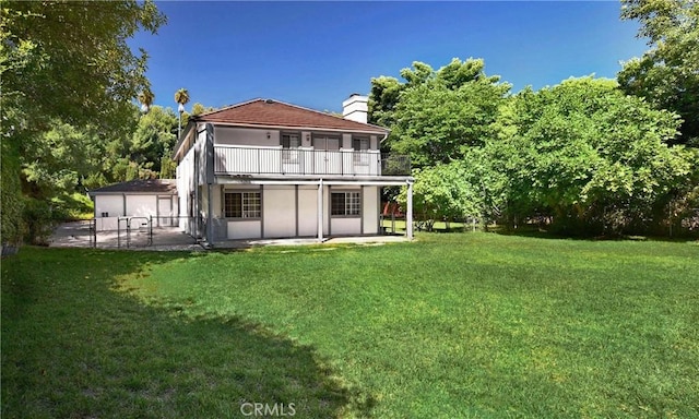 back of house with a yard, a chimney, a patio area, and a balcony