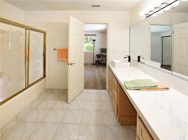 full bathroom featuring tile patterned floors, a sink, visible vents, double vanity, and shower / bath combination with glass door
