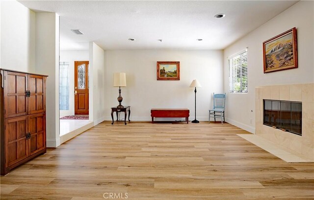 sitting room featuring visible vents, baseboards, a fireplace, and light wood-style floors