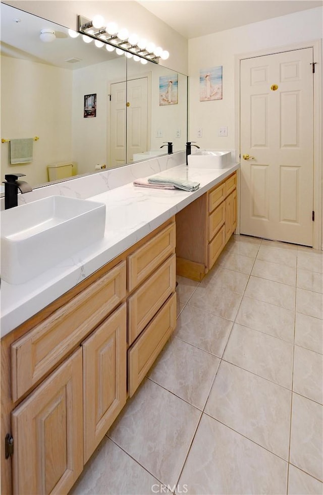full bathroom featuring double vanity, tile patterned flooring, and a sink