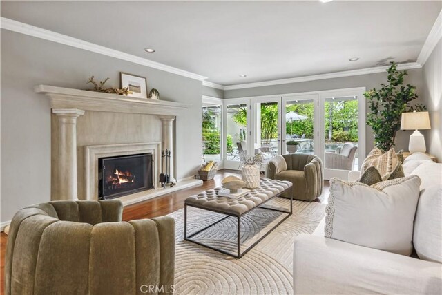 living room featuring recessed lighting, ornamental molding, wood finished floors, and a premium fireplace