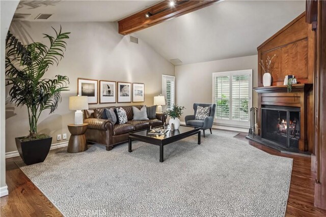 living room with lofted ceiling with beams, baseboards, visible vents, wood finished floors, and a warm lit fireplace