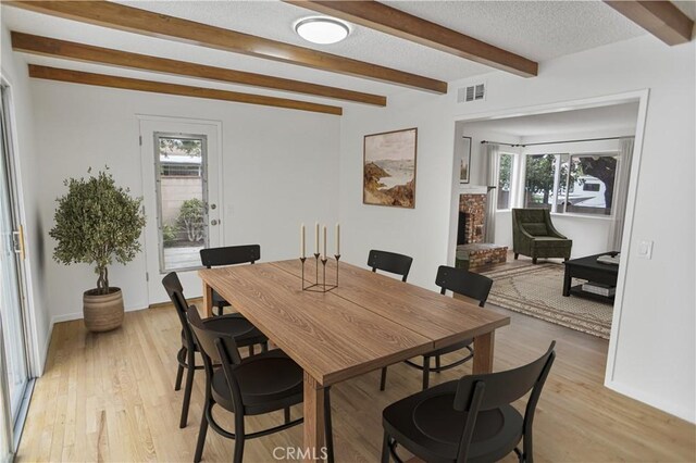 6833 Sultana Ave, San Gabriel, CA 91775 - dining space with healthy amount of natural light, a brick fireplace, beam ceiling, and light wood-style floors