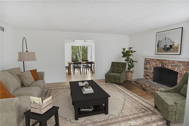 6833 Sultana Ave, San Gabriel, CA 91775 - living room featuring wood finished floors, a brick fireplace, and a textured ceiling