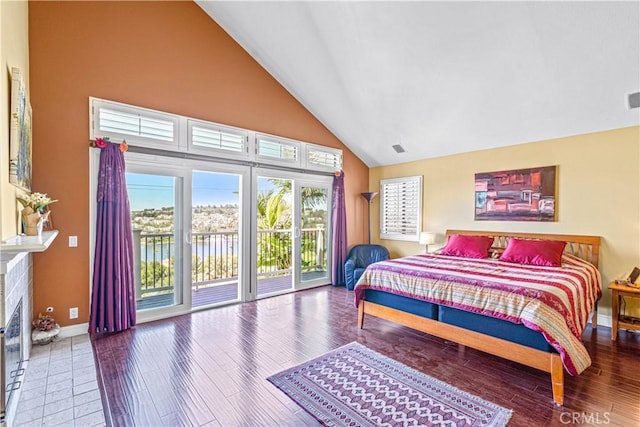 bedroom with a fireplace with flush hearth, access to exterior, baseboards, wood finished floors, and high vaulted ceiling