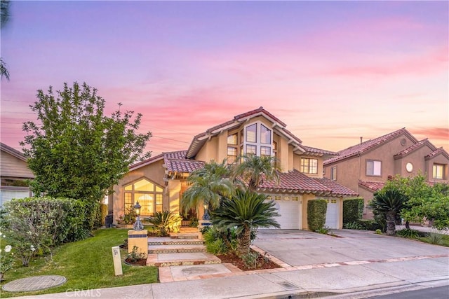 view of front of house featuring a tile roof, a front lawn, a garage, driveway, and stucco siding