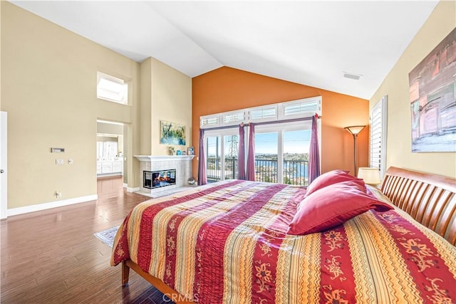 bedroom with high vaulted ceiling, a multi sided fireplace, access to exterior, visible vents, and wood finished floors