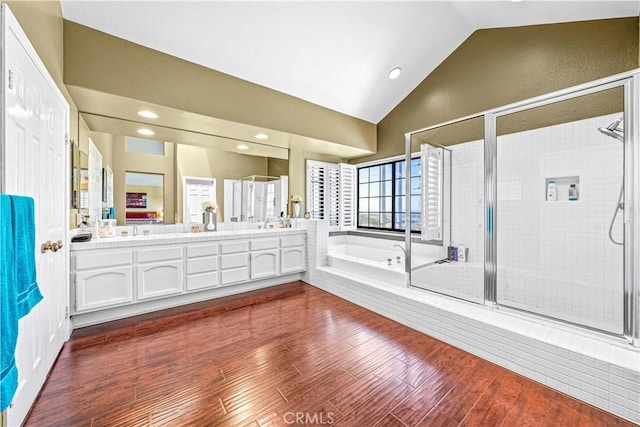 bathroom with a bath, a shower stall, double vanity, and lofted ceiling