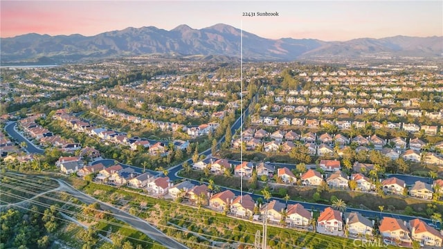 aerial view at dusk featuring a mountain view and a residential view