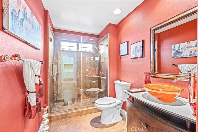 bathroom featuring tile patterned flooring, a shower stall, toilet, a textured wall, and vanity