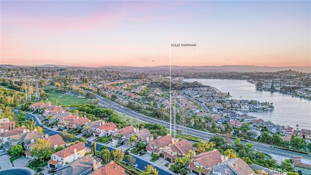 aerial view at dusk featuring a residential view and a water and mountain view