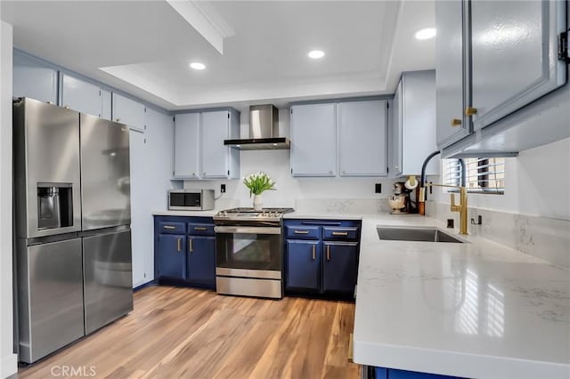 10201 Mason Ave Unit 115, Chatsworth, CA 91311 - kitchen featuring appliances with stainless steel finishes, wall chimney exhaust hood, a sink, a tray ceiling, and blue cabinets