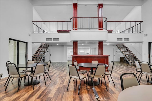 10201 Mason Ave Unit 115, Chatsworth, CA 91311 - dining space featuring stairs, a towering ceiling, wood finished floors, and ornate columns