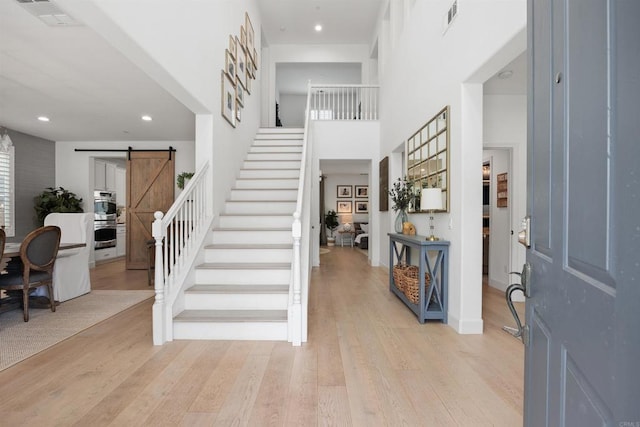 17236 Eagle Canyon Way, San Diego, CA 92127 - entryway with a barn door, stairway, light wood-style flooring, a towering ceiling, and recessed lighting