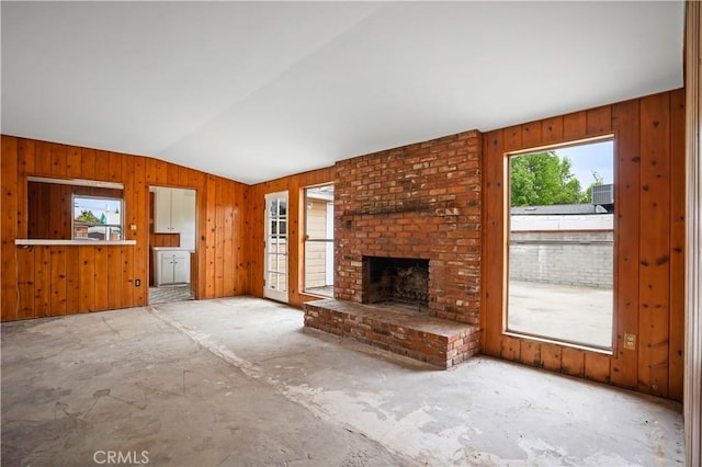 6701 Matilija Ave, Van Nuys, CA 91405 - unfurnished living room with lofted ceiling, a brick fireplace, and wood walls