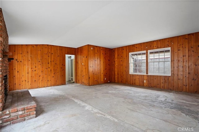6701 Matilija Ave, Van Nuys, CA 91405 - unfurnished room with a brick fireplace, vaulted ceiling, wood walls, and unfinished concrete flooring