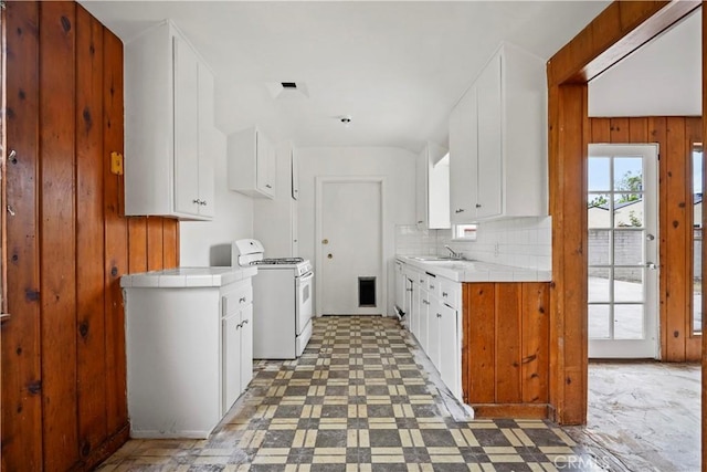 6701 Matilija Ave, Van Nuys, CA 91405 - kitchen with white gas range oven, tile countertops, a sink, light floors, and wooden walls