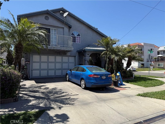 view of front of home featuring stucco siding, an attached garage, driveway, and a balcony
