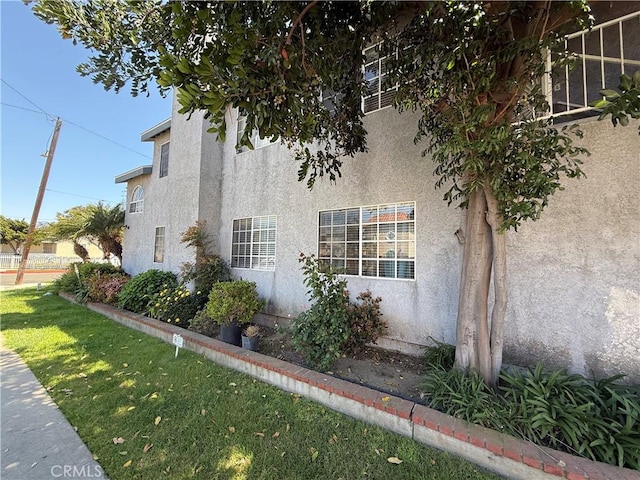 view of home's exterior with stucco siding and a lawn