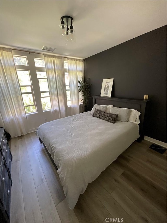 bedroom with baseboards, visible vents, and hardwood / wood-style flooring