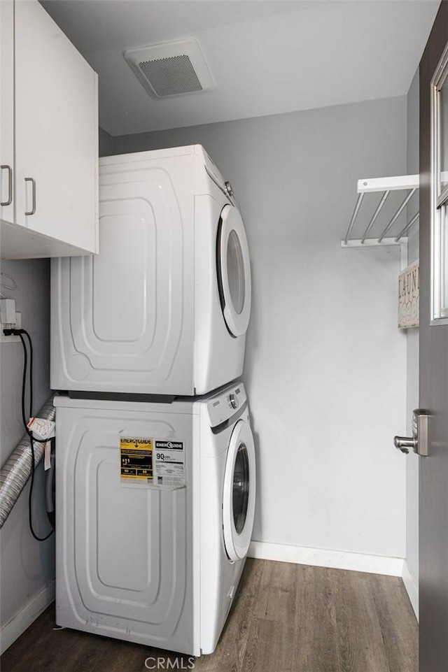 653 Joann St, Costa Mesa, CA 92627 - laundry room featuring cabinet space, stacked washer / drying machine, dark wood-style floors, and baseboards