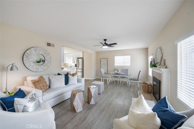 653 Joann St, Costa Mesa, CA 92627 - living room featuring visible vents, light wood-style floors, baseboards, ceiling fan, and a tile fireplace