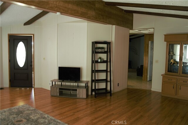 living room with lofted ceiling with beams, baseboards, wood finished floors, and wood walls