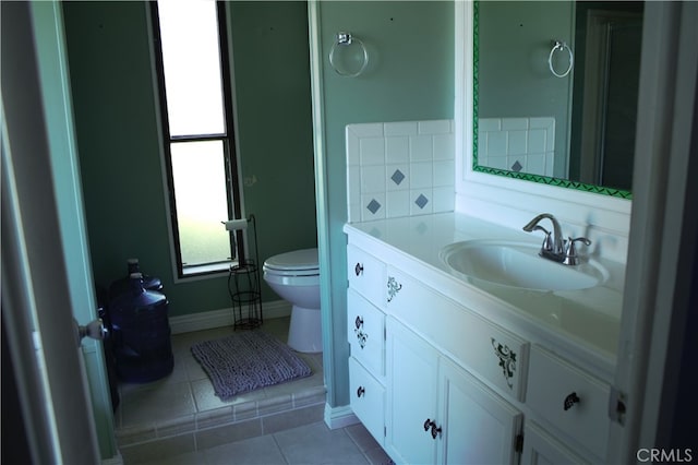 bathroom featuring baseboards, vanity, tile patterned flooring, and toilet