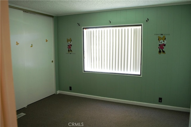 carpeted spare room with visible vents and a textured ceiling