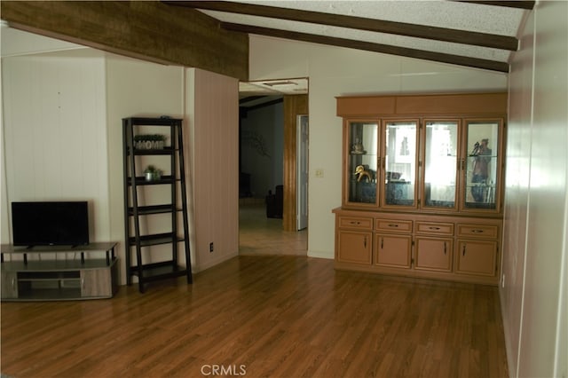 unfurnished living room featuring vaulted ceiling with beams and dark wood-style floors