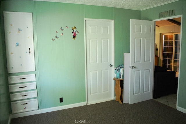 unfurnished bedroom with a textured ceiling, carpet, visible vents, and ornamental molding