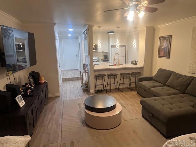 living room featuring a ceiling fan, ornamental molding, and wood finished floors