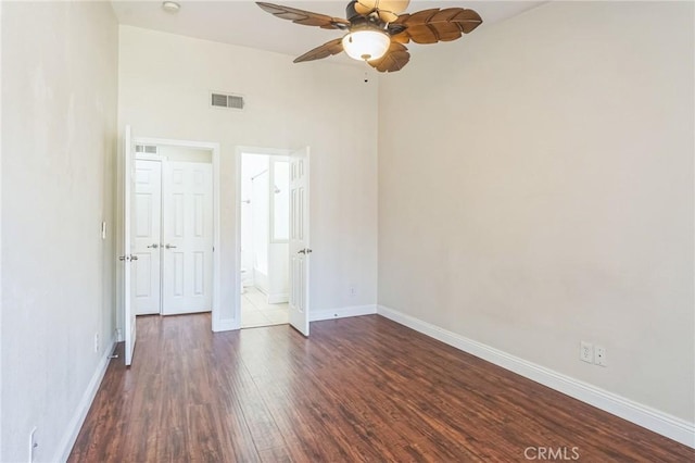 empty room with baseboards, a ceiling fan, dark wood-style flooring, and visible vents