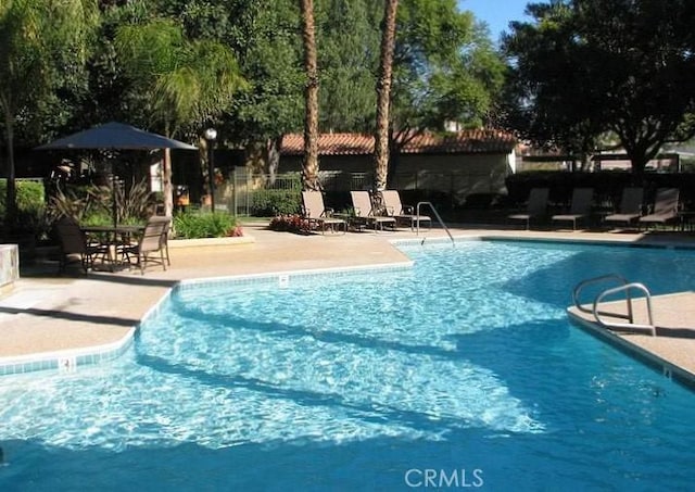 community pool featuring fence and a patio