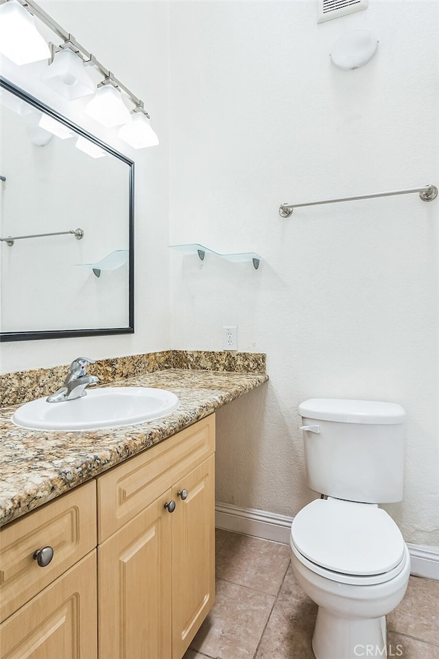 half bath featuring tile patterned flooring, baseboards, toilet, and vanity