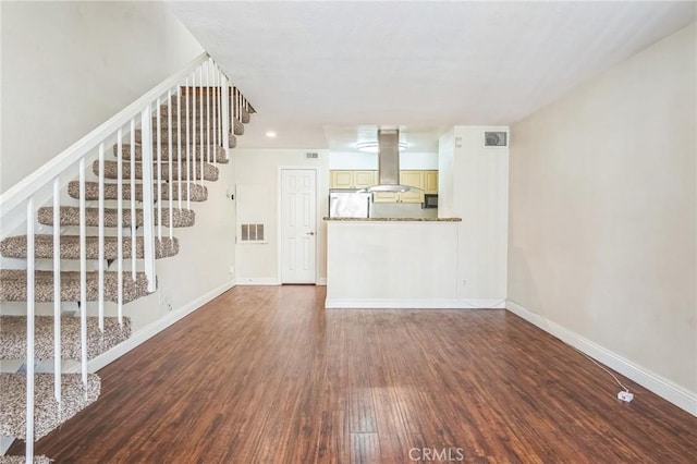 unfurnished living room featuring baseboards, wood finished floors, stairs, and visible vents