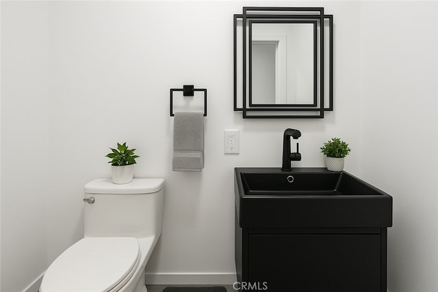 bathroom with toilet, baseboards, and vanity
