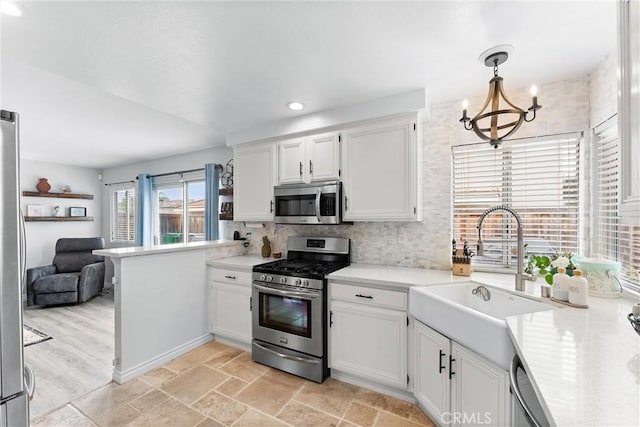 kitchen with light countertops, white cabinets, stainless steel appliances, and a sink