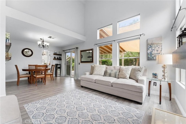 living area featuring light wood-type flooring, baseboards, visible vents, and a notable chandelier