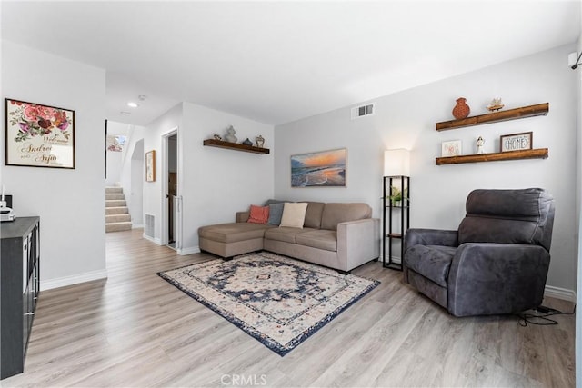 living room featuring light wood-style flooring, baseboards, visible vents, recessed lighting, and stairs