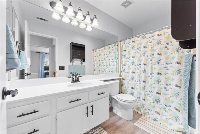 full bath featuring wood finished floors, visible vents, vanity, and toilet