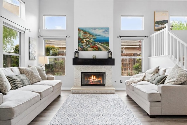 living area with a glass covered fireplace, wood finished floors, and a towering ceiling
