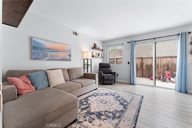 living area featuring visible vents, baseboards, and wood finished floors